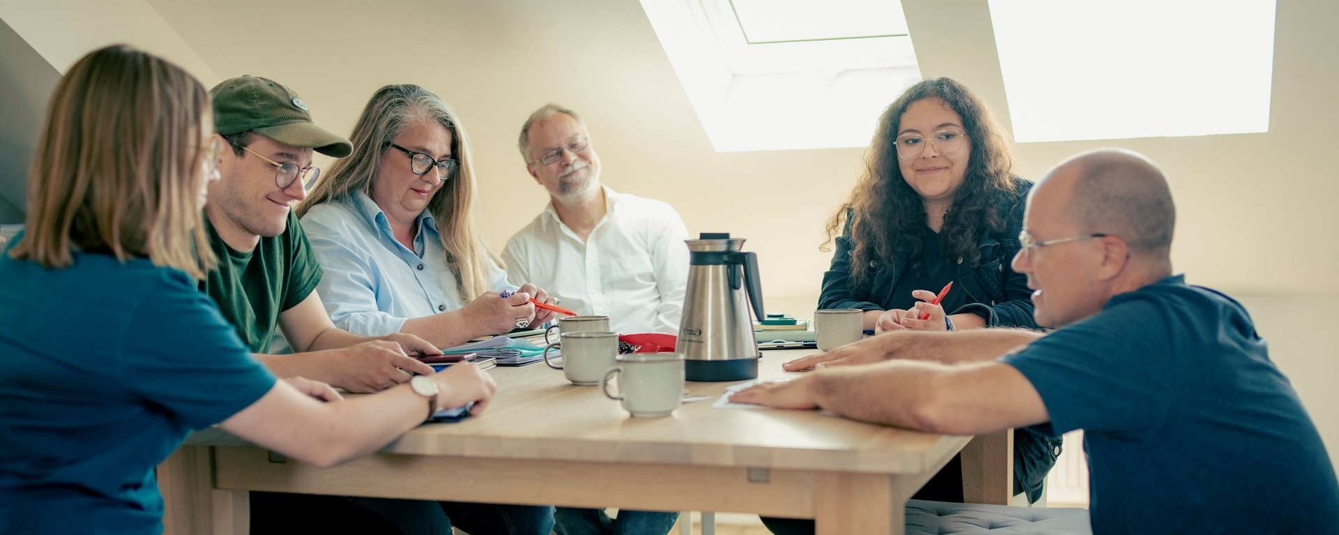 Teambesprechung im Adaptionshaus Kieferngarten, sechs Personen sitzen in einem hellen Raum gemeinsam an einem Tisch